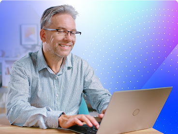 A young female eye care professional wearing scrubs sits beside an older woman with gray hair, both smiling and looking at a laptop screen