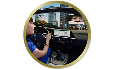 Woman driving a car through the city, looking ahead with her reflection visible in the rearview mirror
