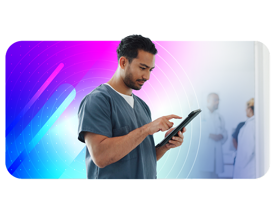 Male healthcare professional in scrubs using a tablet, with medical staff in the background