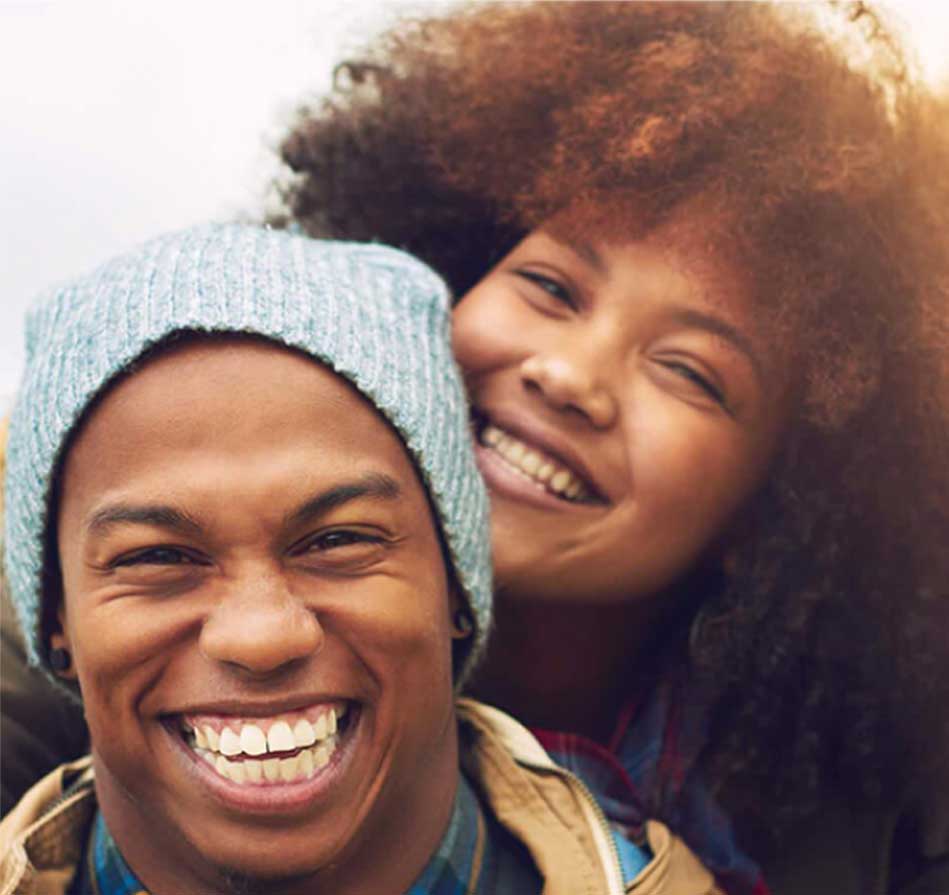 Two people laughing together outdoors, enjoying a bright day