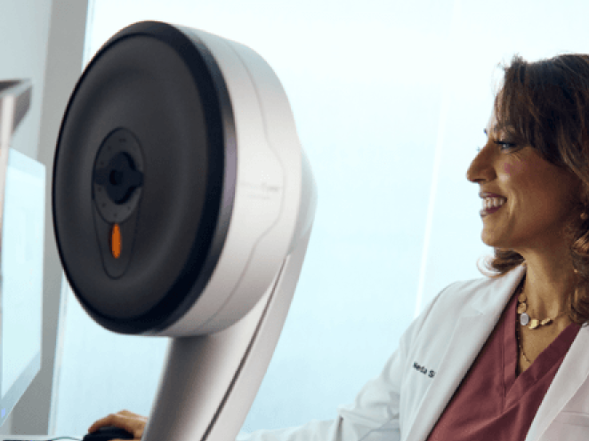 A Doctor in white lab coat standing beside advanced eye care equipment, preparing for a refractive wavelight surgery procedure.